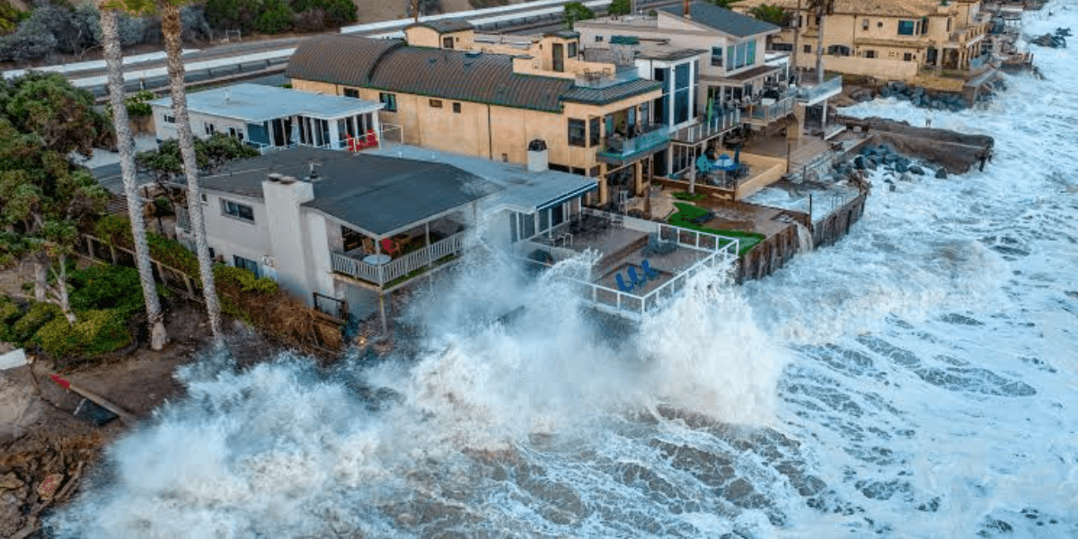 Waves crashing against coastal homes, showing erosion and power of the ocean