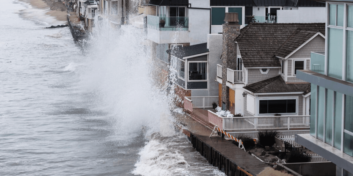 Waves crashing against coastal homes near the edge of the waterline