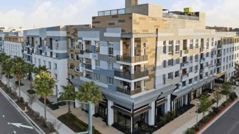 Modern multi-story residential building with palm trees and a wide street in front