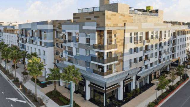 Modern multi-story residential building with palm trees and a wide street in front