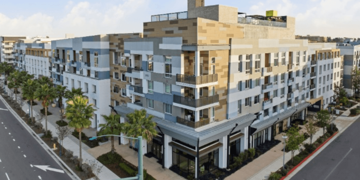 Modern multi-story residential building with palm trees and a wide street in front