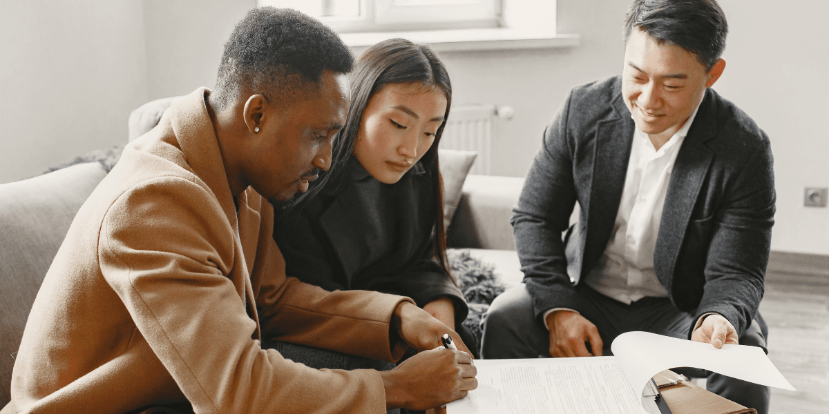 Three people reviewing and signing documents in a cozy indoor setting