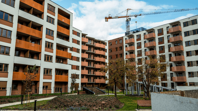 Modern apartment buildings with landscaped courtyard and construction crane in the background.
